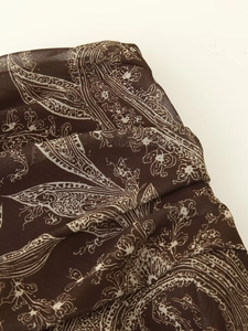 Gros plan sur le tissu en mousseline marron avec motifs paisley blancs et textures