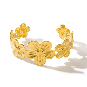 Elegante bracciale aperto in acciaio al titanio dorato con petali di fiori su bianco