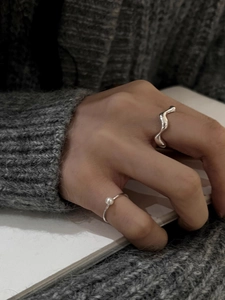 Close-up of minimalist S925 silver wave ring and white pearl ring worn on hand