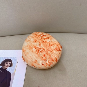 Detail shot of orange marble pattern evening bag with resin finish and snap closure