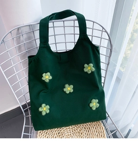 Close-up of deep green canvas bag with five light green 3D crochet flower decorations