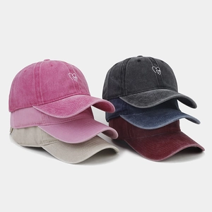 Detailed view of six colors of washed cotton baseball caps with double heart embroidery