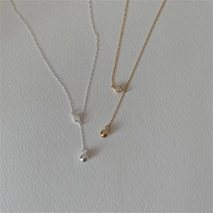 Close-up of minimalist gold and silver dual-tone necklaces with cubic zirconia pendants