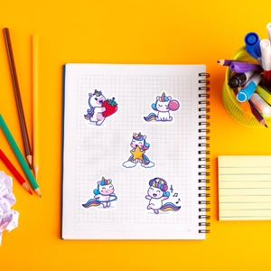 Close-up of cute colorful unicorn stickers for kids on a yellow background and notebook