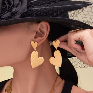 Polished 18k gold plated heart earring set worn by model with matching necklace