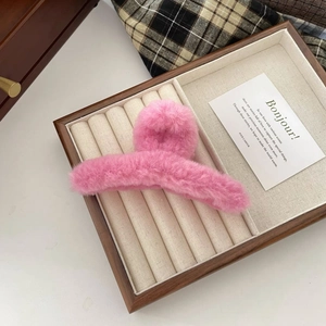 Detailed close-up view of a pink plush hair claw clip on an elegant display tray.