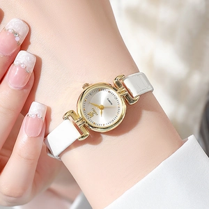 Close-up of elegant small dial quartz watch with rhinestones on a slim white leather strap