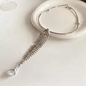 Silver fishbone necklace with a baroque pearl pendant displayed on a white plate