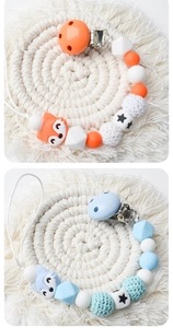 Close-up of handmade silicone fox pacifier clips with crochet beads and wooden star details