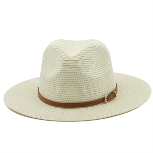 Detailed view of the woven texture and brown leather strap with gold buckle on a straw hat