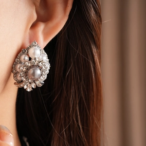 Close-up of vintage baroque silver earrings with clusters of pearls and rhinestones