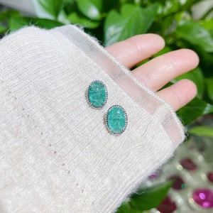 Macro detail of oval green crackle crystal earrings with silver-tone beaded edge