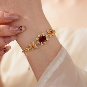 Detailaufnahme eines Vintage-Goldarmbands mit rotem ovalem Zirkon und floralen Steinen