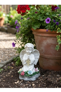 Detalle de estatua de ángel rezando en resina con pequeñas flores de colores en la base