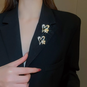 Detail of two intertwined gold heart brooches with crystals on a black suit lapel
