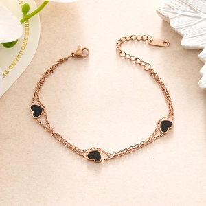 Macro detail of double-layer rose gold stainless steel chain bracelet with black heart charms