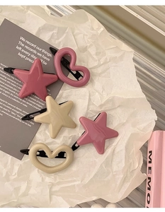 Détail d'un lot de barrettes à cheveux roses en forme d'étoile et de cœur sur papier
