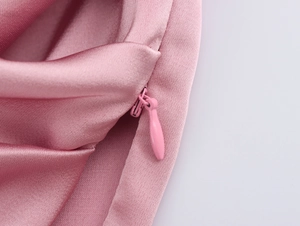 Gros plan sur la fermeture éclair invisible et le tissu en satin rose fluide de l'ensemble