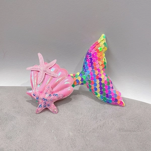 Detail of sequin mermaid tail and pink starfish hair clips with a shell design