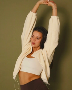 Detail shot of off-white fleece zip-up hoodie and dark brown high-waist yoga leggings