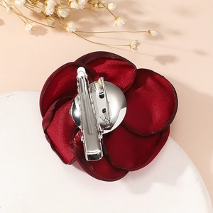 Red fabric rose brooch with dual silver clip and pin back shown on a white display
