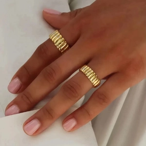 Fashionable 10mm wide gold rippled texture ring worn by model on white shirt background