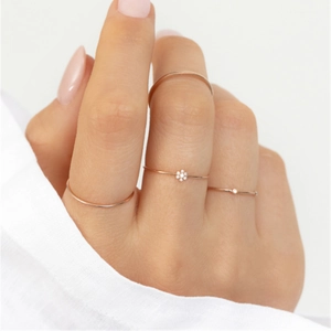 Detailed view of three minimalist rose gold rings featuring floral and dot accents