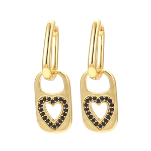 Golden earrings with hollow heart pendants and black zircon inlay on a white background