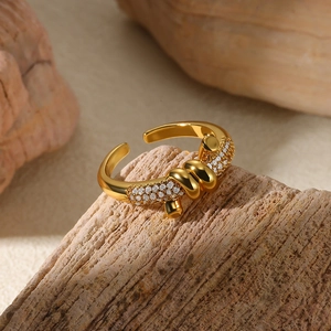 Macro detail of gold knot ring with white zircon stones on a rustic wood background