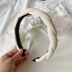 Close-up of cream white braided headband with sponge padding and non-slip inner teeth