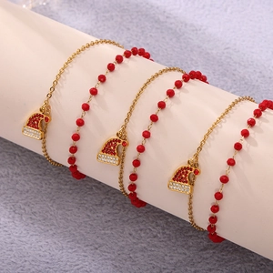 Detailed view of golden Christmas bracelets with red beads and Santa hat charms on white stand