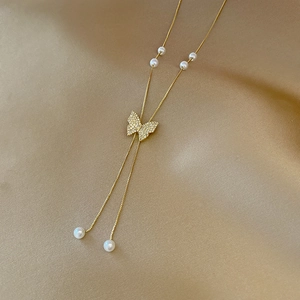 Élégant collier papillon en acier titane doré avec perles blanches et pompons brillants