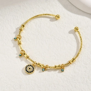 Macro detail of gold Evil Eye cuff bracelet with blue zircon charms and textured finish