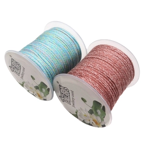 Two spools of braided cotton jewelry cord in gradient blue-green and dark red colors