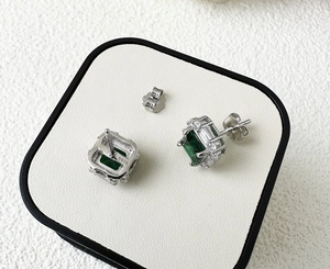 Detail of S925 silver stud earrings with a rectangle green stone and halo of zircons