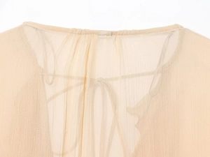 Detail of sheer beige blouse showing adjustable lace-up neckline and ruffle texture