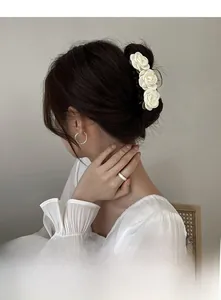 Detailed view of triple white camellia flower hair claw clip on elegant wavy hair