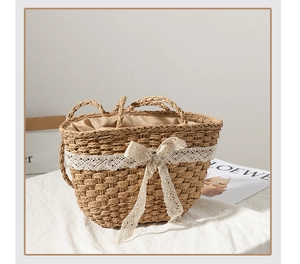 Detail of handmade straw bag featuring elegant lace trim and a bow on white fabric