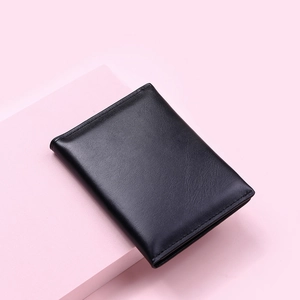 Detail shot of a black soft PU leather wallet with buckle on a pink geometric stand