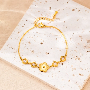 Macro shot of 18K gold plated flower and zircon star pendants on a delicate link bracelet