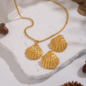 Dettaglio del set collana e orecchini a conchiglia dorata su base in marmo bianco