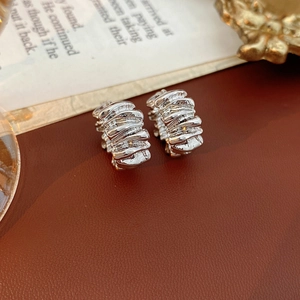 Detailed macro view of silver irregular liquid metal earrings on a leather surface