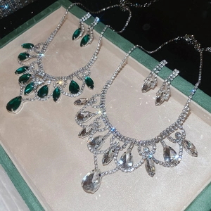 Detailed view of luxury silver teardrop necklaces and earrings with green and white gems