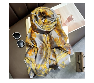 Detail of gray silk scarf with golden baroque patterns laid out with accessories
