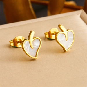 Macro detail of gold leaf heart earrings with white mother of pearl inlay on velvet