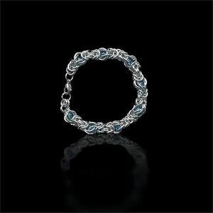 Détail d'un bracelet en chaîne argentée avec zircons bleus et fermoir mousqueton