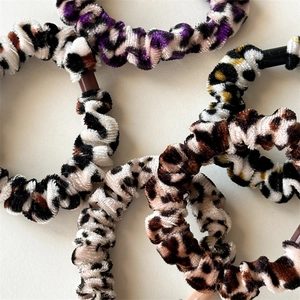 Detail of four high-elastic velvet leopard print scrunchies in various colors