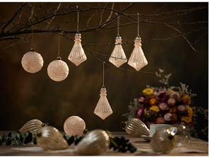 Detail of pink and champagne textured glass Christmas ornaments on a tree and fabric