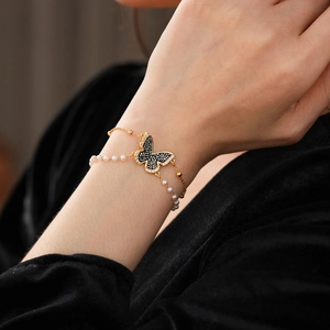 Detailed macro of gold plated double-layer butterfly bracelet with pearls and crystals
