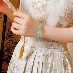 Detail of a light green jade bangle worn by a model in elegant New Chinese style attire